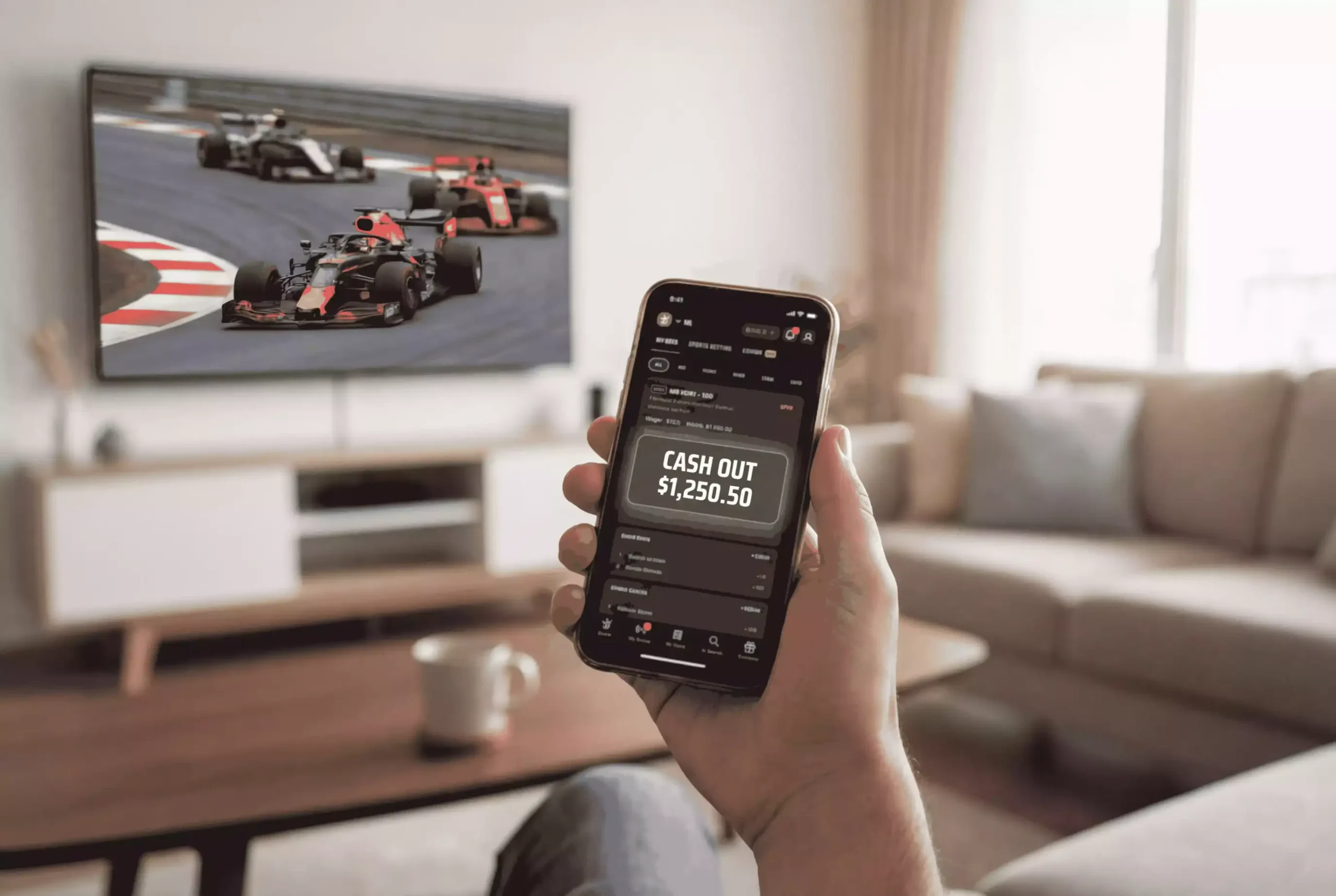 Smartphone mit einer Sportwetten-App und Cash-Out-Button während eines Formel-1-Rennens
